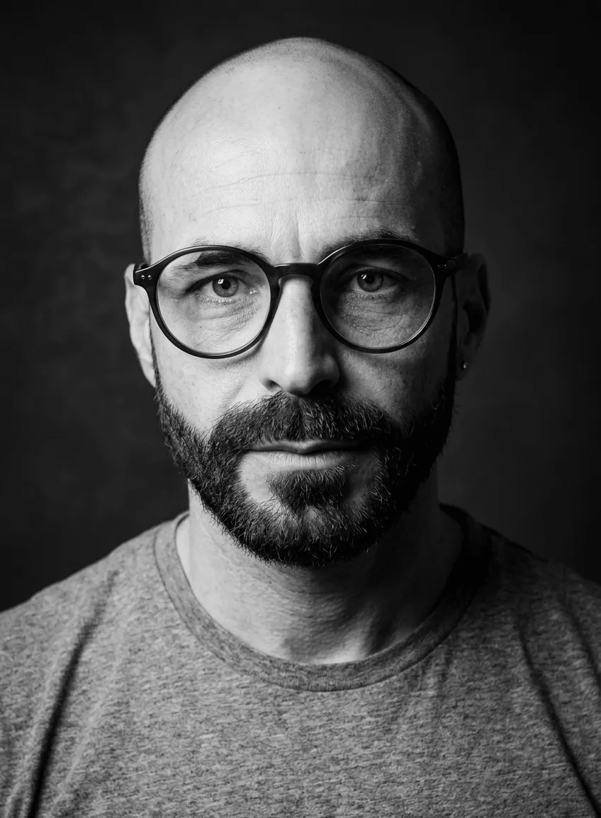 Retrato em preto e branco de Wagner Barbosa usando óculos e barba, utilizado como capa do vídeo do canal Voz em Construção.